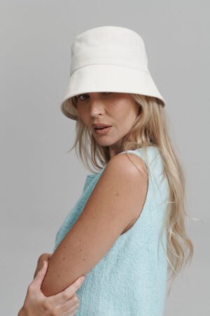 Model wearing a cream Coast Bucket cotton bucket hat, showcasing its relaxed style.