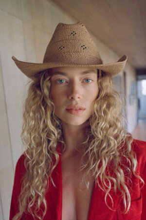 Model wearing a Desert Rose straw cowboy hat in tan color, featuring a western style.