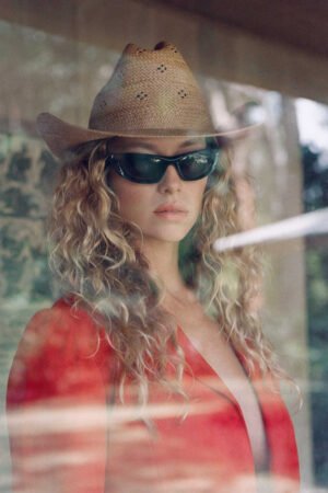 Model wearing a Desert Rose tan straw cowboy hat with sunglasses, showcasing a western style.