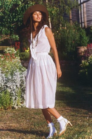 Model wearing a brown cotton bucket hat in a garden setting