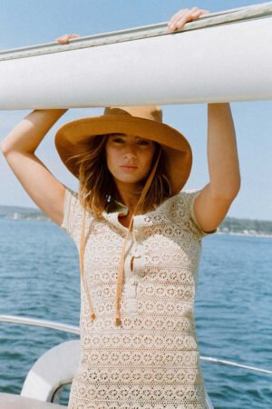 Model wearing a tan corduroy bucket hat on a boat by the water
