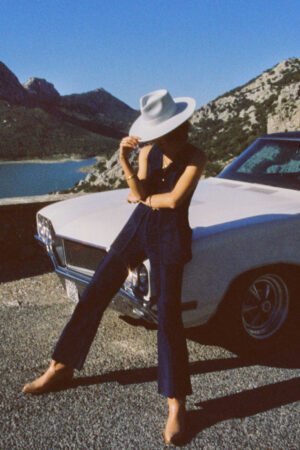 Model wearing a mint wool felt rancher hat, standing beside a vintage car with mountains in the background.