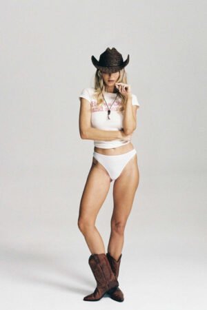 Model wearing the Phoenix Cowboy straw hat in brown, styled with a white outfit and cowboy boots.