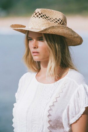 Model wearing Seashells Cowboy straw hat by the beach