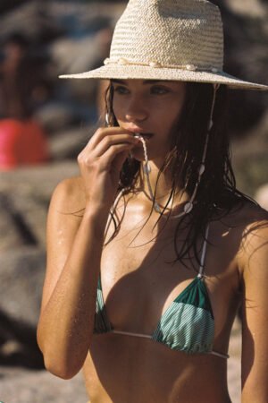 Model wearing Seashells Fedora hat at the beach, with a chin strap and seashells.