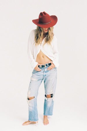 Model wearing The Ridge Special wool felt cowboy hat in red, styled with a white shirt and distressed jeans.