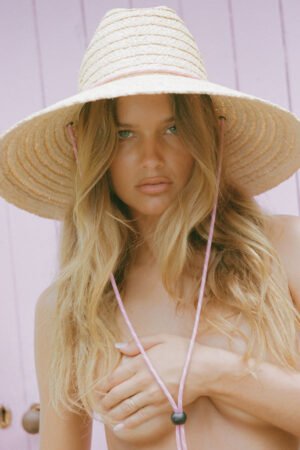 Model wearing The Vista straw cowboy hat with a pink chin cord against a pink background