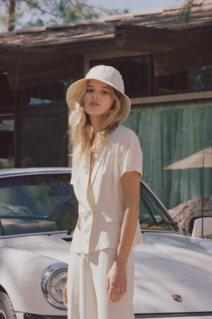 Model wearing a beige Wave Bucket Hat outdoors, standing next to a white car.