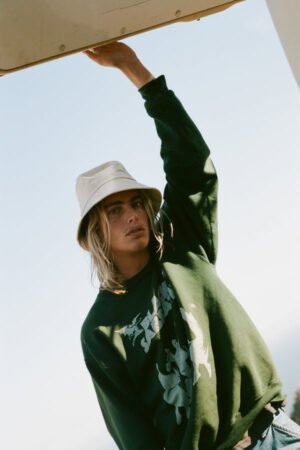 Model wearing a beige cotton bucket hat, styled with a green sweatshirt.