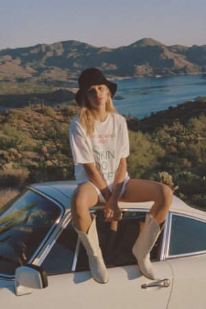Model wearing a black Wave Bucket Hat, sitting on a car with mountains in the background.