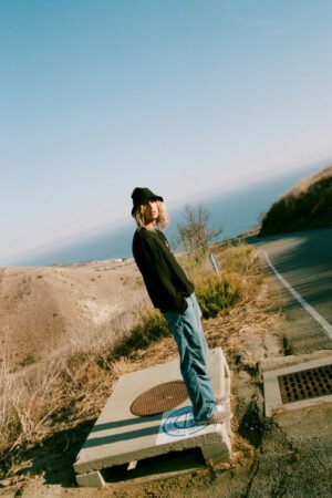 Person wearing a black Wave Bucket Hat standing on a roadside with a scenic view in the background.